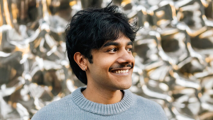 Portrett av Praval; mørkt hår; smil; grå genser