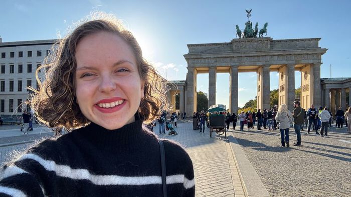 Cecilie smilende foran byporten Brandenburger Tor i Berlin