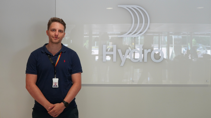 Portrettfoto av Ulrik foran Hydro-logo