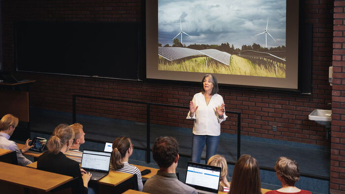 En professor som foreleser i en sal med studenter.