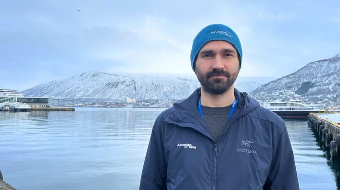 Foto av Magnus med havet og snøkledde fjelltopper i bakgrunnen.