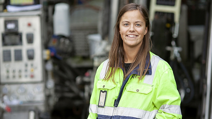 geolog i godt synlige arbeidsklær foran maskineri