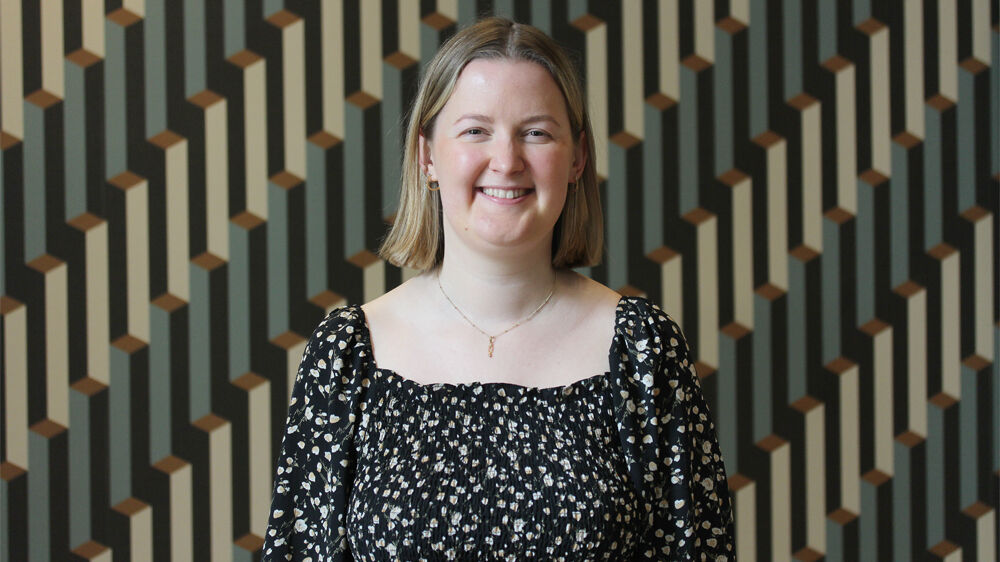 Portrettfoto av intervjuobjekt inne foran tapet.