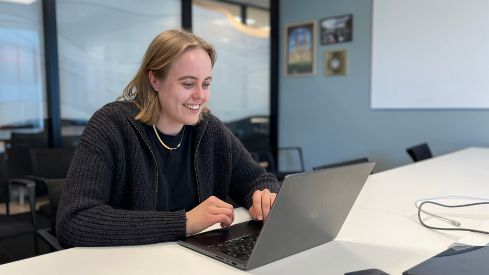 Jente sittende i stol, smiler mot kamera
