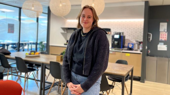 Jente i kontorlandskap som smiler til kamera. 