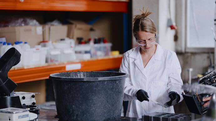 Ung dame med blondt hår på laboratoriet for å teste betong.