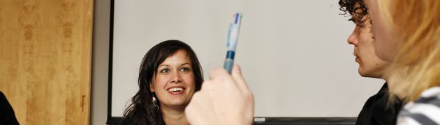 En person holder opp en penn, mens en annen smiler