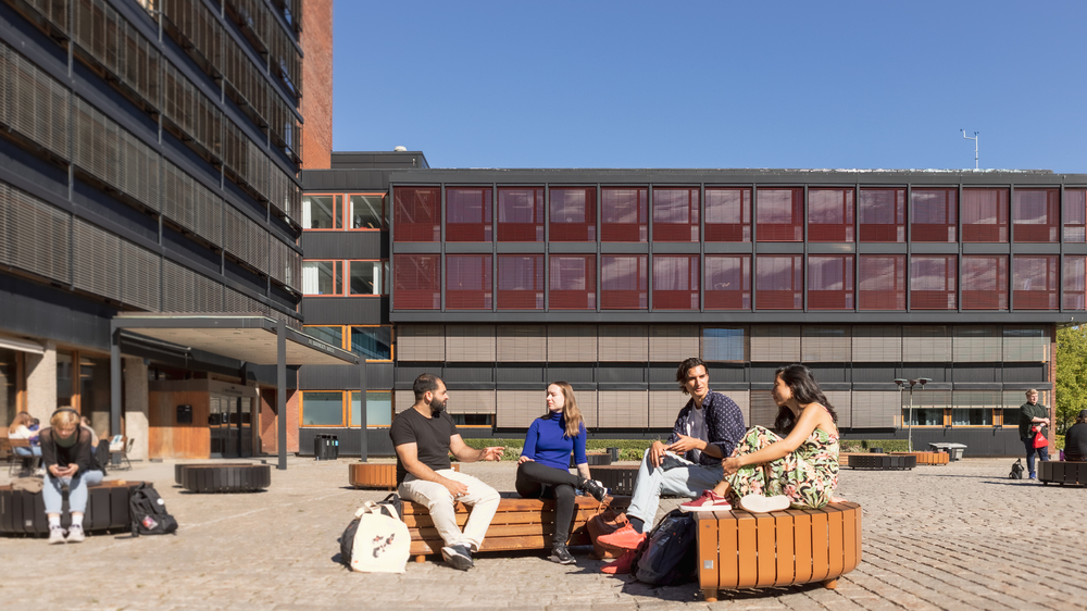 Studenter sitter utenfor Det humanistiske fakultet