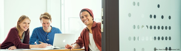 Tre studenter smiler til kameraet