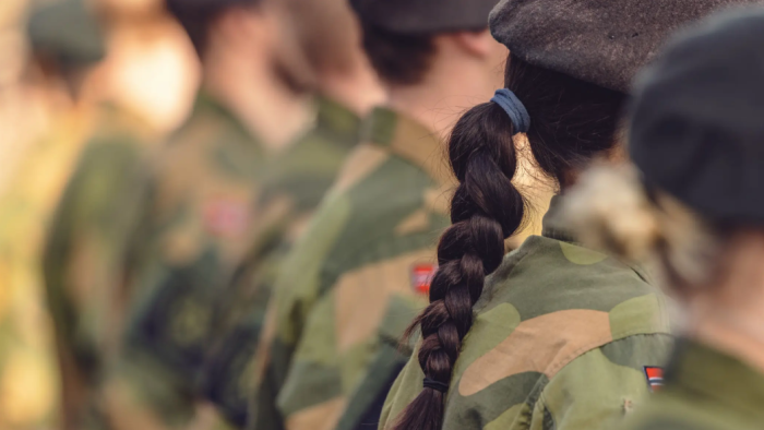 Mennesker i Forsvarets uniform sett bakfra, uklart fokus, jente med flette tydelig.