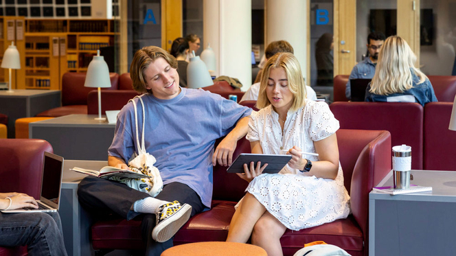 To UiO-studenter sitter i sofa og ser på en iPad